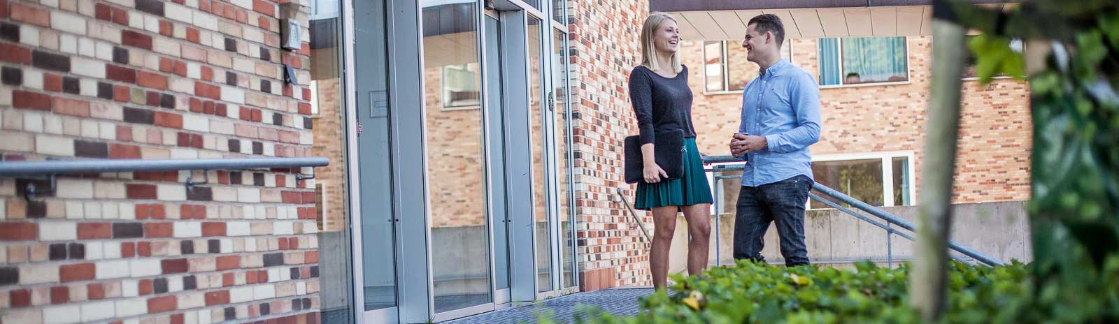 Two students talking outside university building Photo: Jesper Rais for Aarhus University